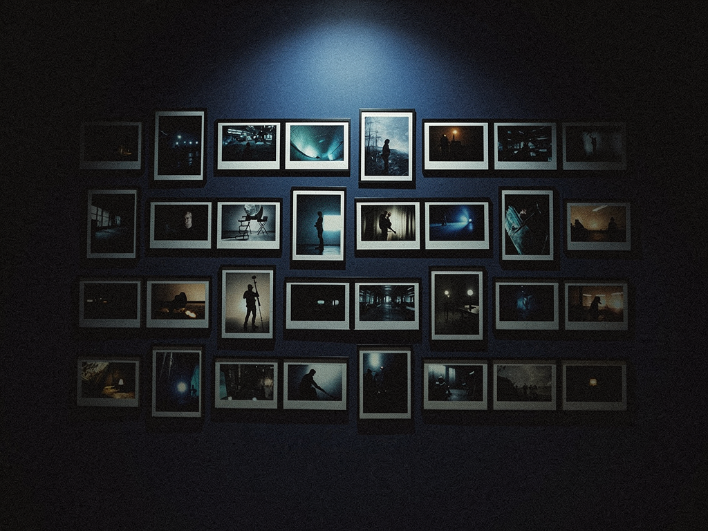 A wall of framed reference stills under a single spotlight — a director's selection wall